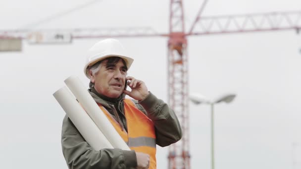 Ingeniero en un casco hablando por teléfono inteligente — Vídeos de Stock