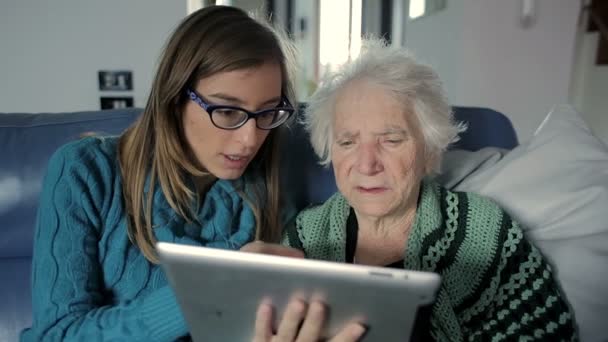 Внучка учит бабушку пользоваться планшетным ПК — стоковое видео