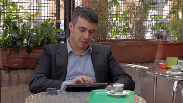 Businessman working on tablet computer and drinking coffee in cafe — Stock Video