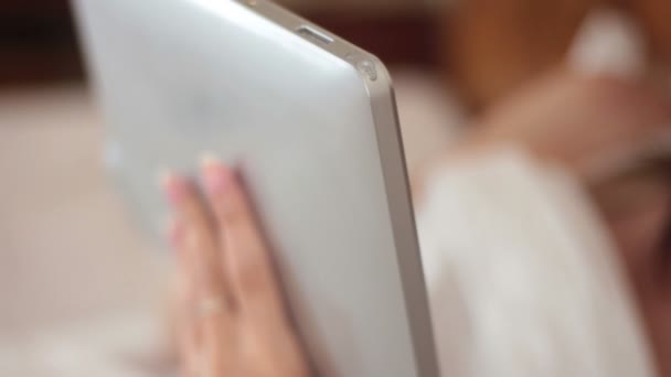 Молода красива жінка використовує на ліжку і тримає цифровий планшет — стокове відео