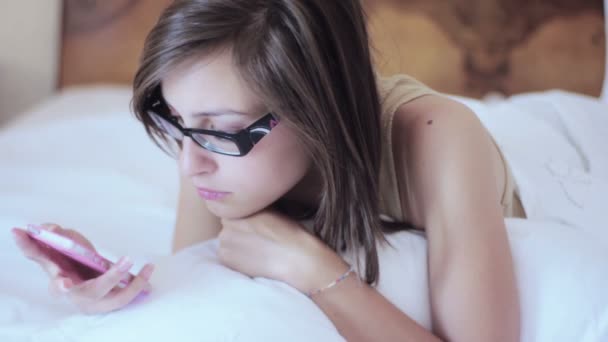 Vrouw met smartphone in bed — Stockvideo