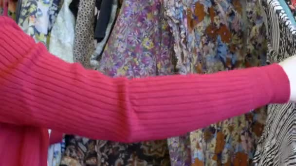 Jonge vrouw op zoek naar goedkope kleding in een winkel: koopje, korting, evenwicht, sp — Stockvideo