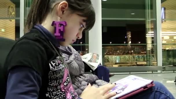 Young woman playing a game with a tablet computer sitting on the bench — Stock video