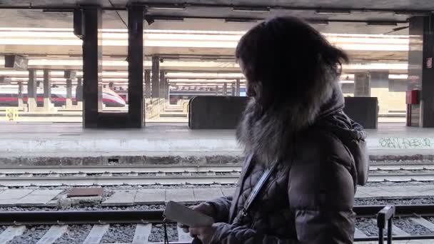 Mujer con smartphone esperando el tren: salida, estación, viaje — Vídeo de stock