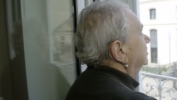 Задумчивая старуха у окна и зрелая дочь, обнимающая ее — стоковое видео
