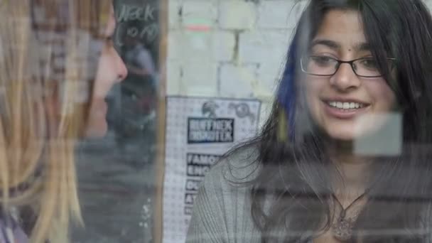 Две подруги болтают сидя в кафе у окна — стоковое видео
