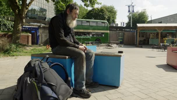 Dakloze man zitten in een stadsplein — Stockvideo