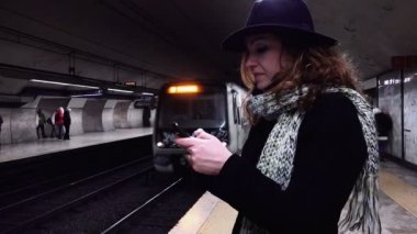 süre gelen tren metro istasyonu bir akıllı telefon kullanan genç kadın