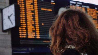 arka planda modern tren Uçus tarifesi ile tren istasyonunda bekleyen kadın