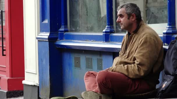 Without a roof over one's head. Homeless man sit on the side walk — Stock Video