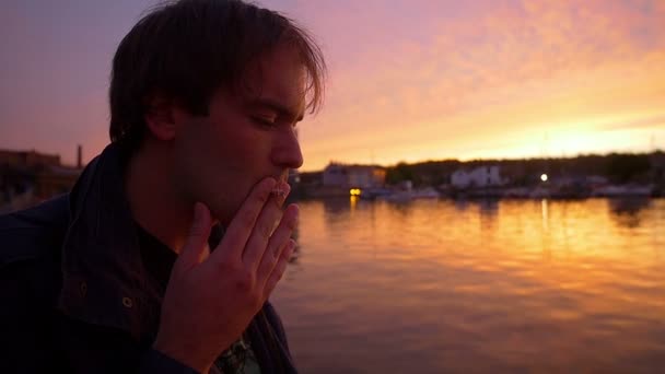 Fundersam man rökning på solnedgången framför hamnen — Stockvideo