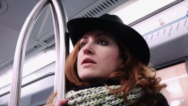 Задумчивая рыжая женщина в шляпе в поезде метро — стоковое видео