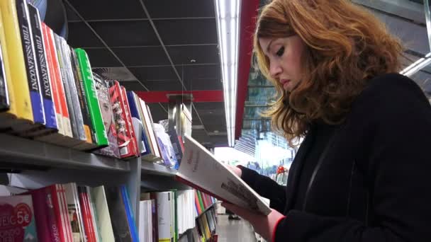 Kultivovaný mladá žena čte Některé knihy v knihkupectví — Stock video