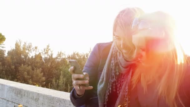 Making a selfie at the sunset: two female friends taking pictures — Stockvideo