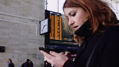 kadın manifatura bir mesaj ve istasyonda tren saat tablo denetimi