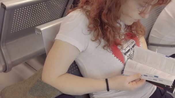 Νεαρή γυναίκα διαβάζοντας ένα τουριστικό οδηγό στο αεροδρόμιο — Αρχείο Βίντεο