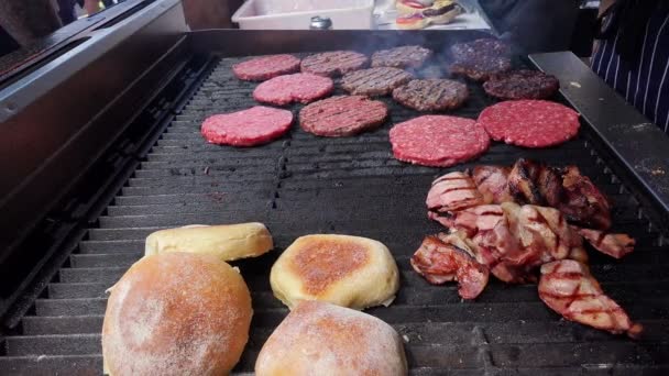 Burger shop - hamburgers with bacon and bread on grill — Stock Video