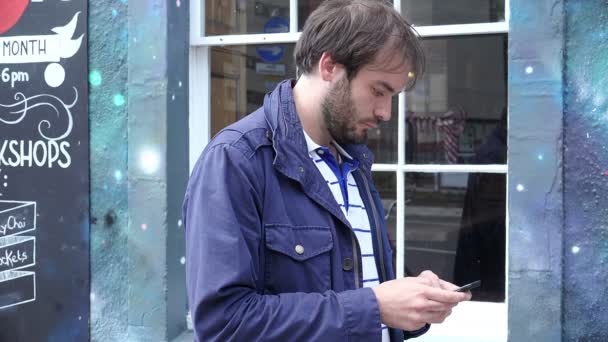 Jovem usando smartphone para enviar mensagens perto de uma vitrine — Vídeo de Stock