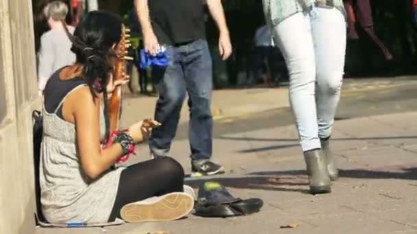 Женщина нищая уличная артистка играет на тротуаре — стоковое видео