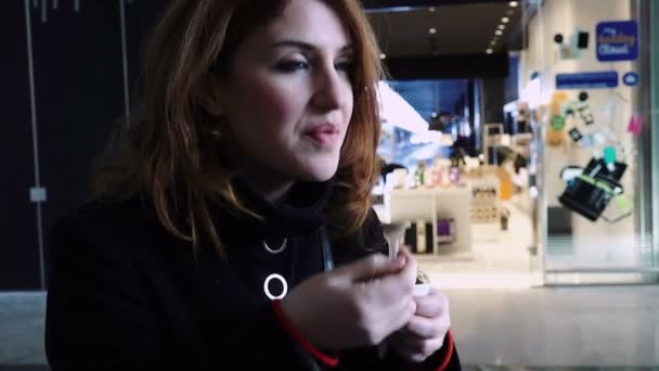 Frau isst Eis, während sie auf den Zug wartet: Pendlerin im Bahnhof — Stockvideo