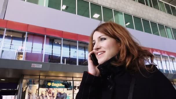 Mujer hablando en el teléfono móvil dentro de una estación de tren — Vídeos de Stock