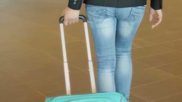 Mujer joven con un carro de equipaje — Vídeo de stock