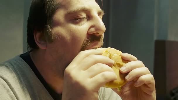 Самотній чоловік їсть гамбургер — стокове відео