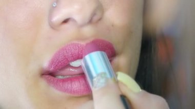 Dudaklarına ruj süren bir kadın.