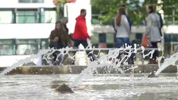 Chorro de agua de una fuente con gente caminando en el fondo: cámara lenta — Vídeo de stock