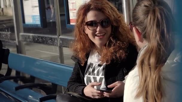 Двое друзей разговаривают на автобусной остановке: дружба, счастье — стоковое видео