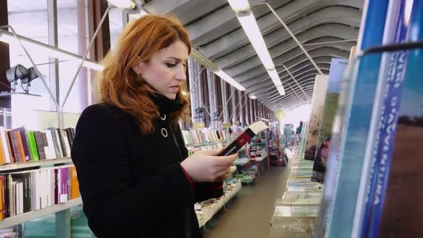 Mulher à procura de um livro em uma livraria — Vídeo de Stock