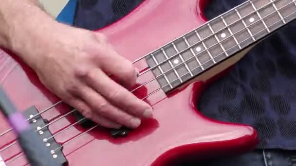 Detail of a musician playing a red electric bass guitar. — Stock Video