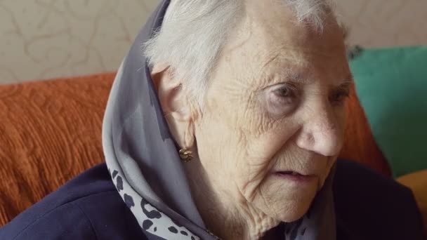 Θλιβερή ηλικιωμένη γυναίκα που κάθεται στον καναπέ — Αρχείο Βίντεο