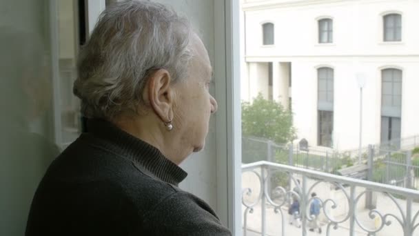 Старая депрессивная женщина смотрит в окно — стоковое видео