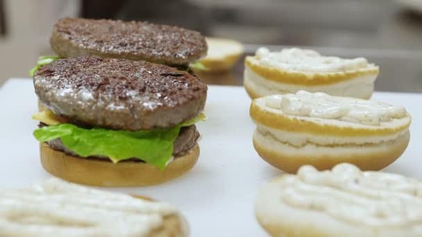 Preparação de alimentos: Cook realiza sanduíches com hambúrguer — Vídeo de Stock