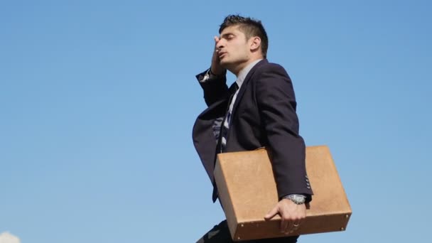 Hombre de negocios cansado en la cima de una montaña — Vídeos de Stock