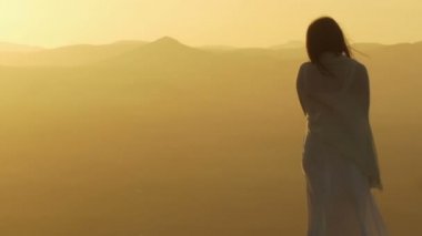 kadın bir dağın tepesinde batımında