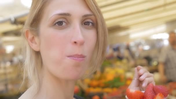 Mujer comiendo frutas en el mercado — Vídeos de Stock