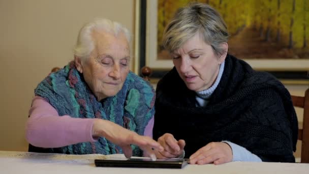 Ancianas centradas en el uso de la tableta sentarse en el escritorio — Vídeo de stock