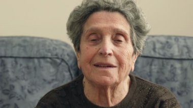 yaşlı kameraya gülümseyen kanepede oturan kadın