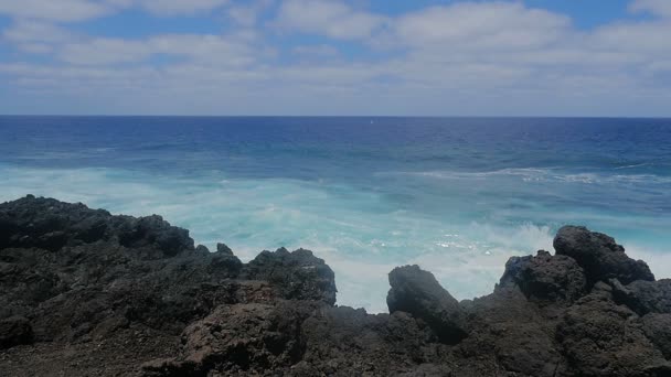 Blick von oben auf das kristallklare Meer und seine Wellen, die an den Felsen brechen — Stockvideo