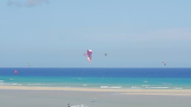 Fuerteventura lidé dělají kitesurfing v křišťálově čistém moři za slunečného dne — Stock video