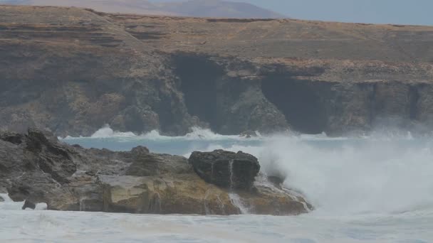 Fuerteventura - yavaş hareket bakış dalgalar fırlama kendilerini uçurumun karşı bulutlu bir günde — Stok video