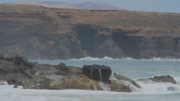 フェルテベントゥラ島 - 波のスローモーションの概要が曇りの日に崖に対して彼ら自身を投げつける — ストック動画