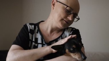Arkadaşlık, şefkat, kemoterapi gören kel bir kadın köpeğini okşar.