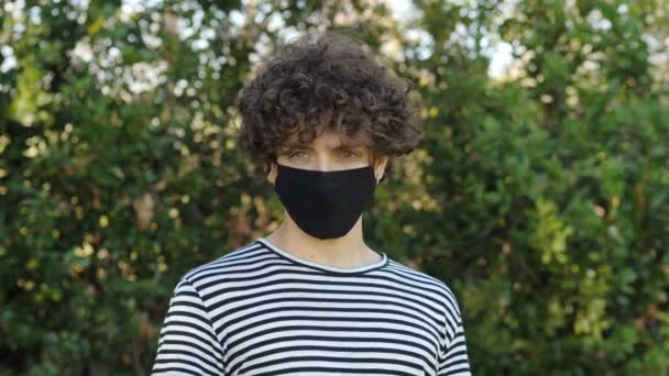 コロナウイルス距離 マスクをした若い男はカメラを作らない — ストック動画