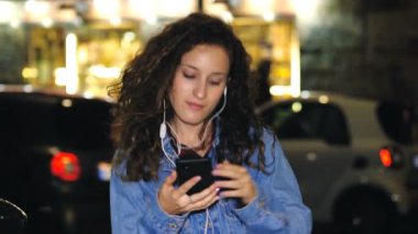 Podcast, teknoloji - kız gece sokakta müzik dinliyor.