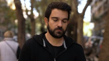 Kurallara uy. Genç adam kameraya bakıyor. Açık havada bile maske takıyor.
