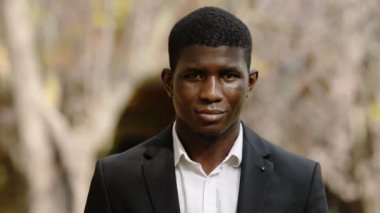 Gençlik, kendine güven - genç ciddi siyah adam kameraya gülümseyen yüz ifadesini değiştirir