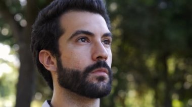 Parkta genç çekici bir adam dua ediyormuş gibi yukarı bakıyor.